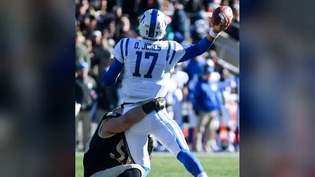 Daniel Jones in a white Duke No. 17 jersey throws a pass as an Army defender wraps him up at Michie Stadium in November 2017