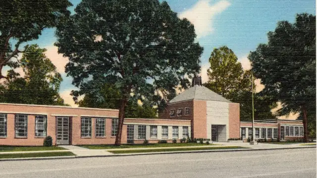 A vintage postcard view of the brick Municipal Building in Crossett, Arkansas, framed by tall shade trees
