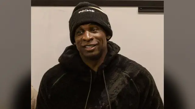 Deion Sanders in a black knit cap and dark jacket smiles during a 2024 visit with U.S. Marines