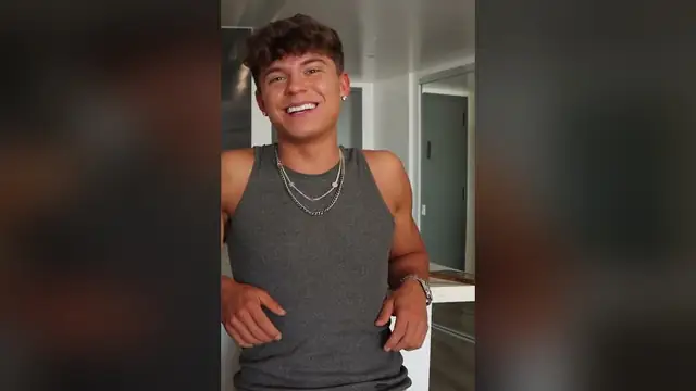 Adult film actor Drake Von smiling in a gray tank top during a sit-down interview