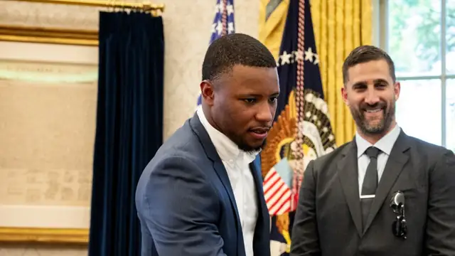 Eagles running back Saquon Barkley in a blue suit stands beside coach Nick Sirianni during a 2025 White House visit