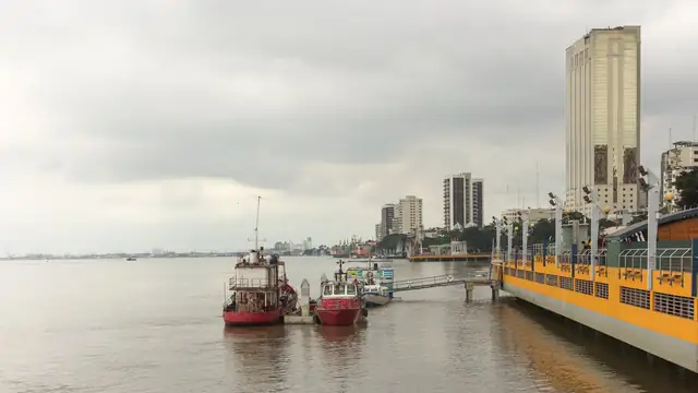 Boats docked along the Guayas River waterfront in Guayaquil with high-rise towers behind them