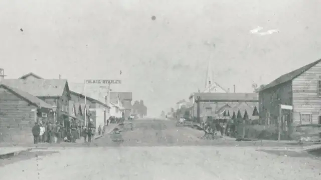 Black and white 1885 photo of a dirt street in Eureka's Chinatown lined with wooden buildings and groups of people