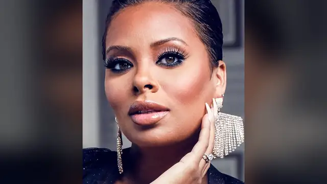 Eva Marcille with slicked-back hair large crystal earrings and a diamond ring posing with her hand near her face