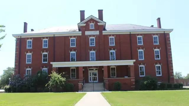 Red brick Huntington Hall with a white columned entrance behind a green lawn on the Fort Valley State University campus
