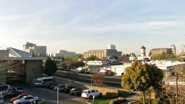 Low buildings and parked cars in downtown Fresno under a pale sky
