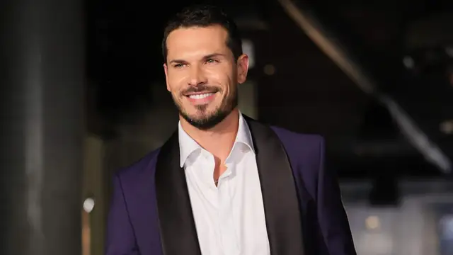 Gleb Savchenko smiling in a purple tuxedo jacket and open white shirt
