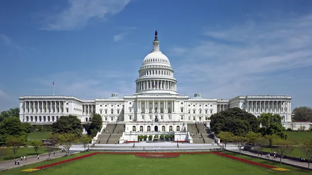 West front of the United States Capitol under a clear blue sky with the dome centered above the steps