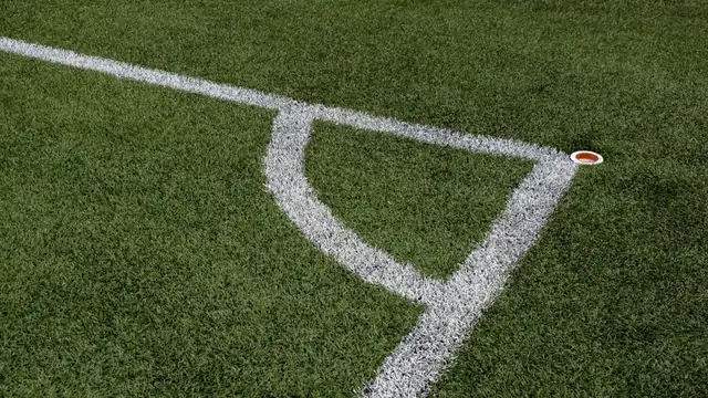 A white corner marking on a green artificial turf field