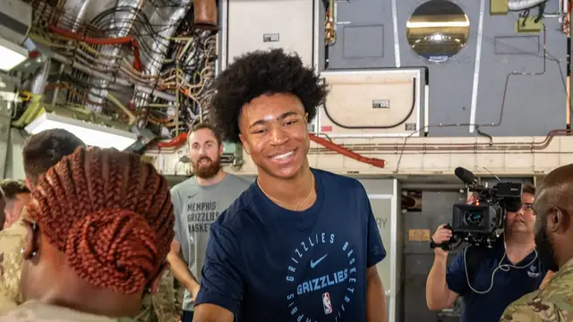Grizzlies forward Jaylen Wells smiles in a navy Grizzlies T-shirt while greeting airmen inside a cargo plane in Memphis