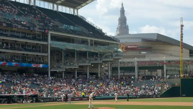 Fans fill the lower deck at Progressive Field in Cleveland on a sunny afternoon with the Terminal Tower rising beyond the ballpark