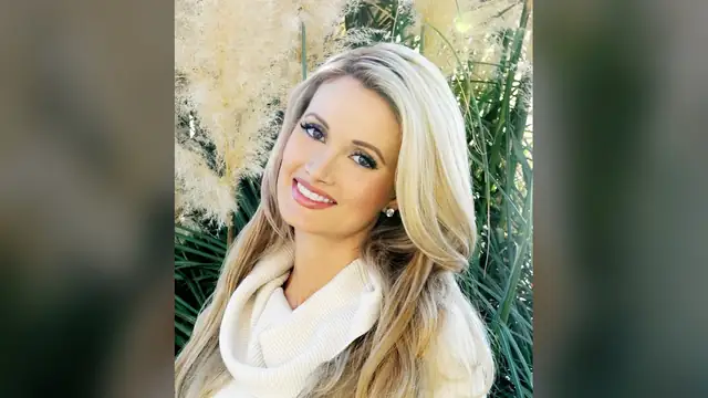 Holly Madison smiling in a cream turtleneck in front of tall grasses