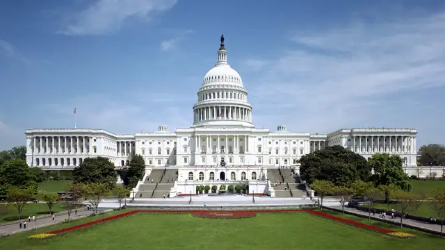 West front of the U.S. Capitol with the dome rising above trees on a clear day