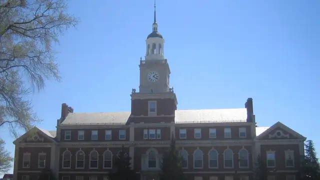 Founders Library at Howard University with its brick clock tower rising above the campus under a clear blue sky