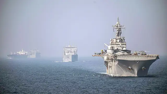 The amphibious assault ship USS Essex and a Navy cargo ship sailing in formation through the hazy Strait of Hormuz