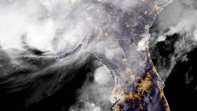 Night satellite view of the storm's clouds spreading over Alabama and the Florida Panhandle at landfall with city lights glowing across Georgia and Florida