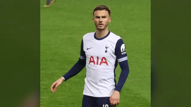 James Maddison in a white Tottenham kit stands on the pitch during a match against Rangers in December 2024