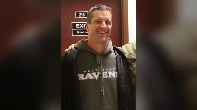 John Harbaugh smiles in a gray Ravens hoodie during a February 2014 visit with U.S. troops at Kandahar Airfield in Afghanistan