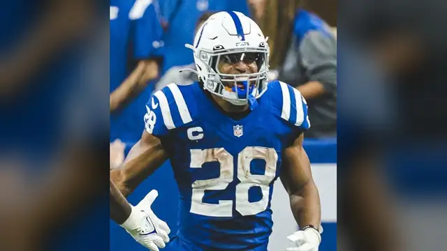 Colts running back Jonathan Taylor smiling under his helmet in the blue No. 28 jersey with a captain's patch during a home game