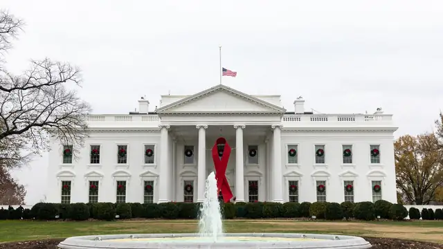 North facade of the White House with the American flag flying above the portico on a clear day