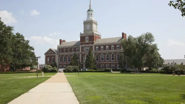 A paved walkway crosses a green lawn toward Founders Library and its white clock tower at Howard University