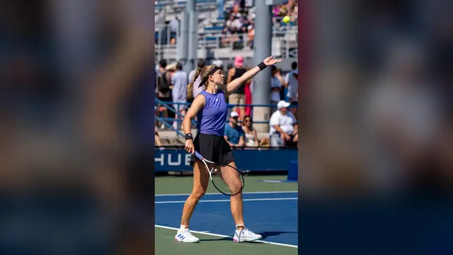 Karolina Muchova in a purple top tosses the ball to serve at the 2024 US Open