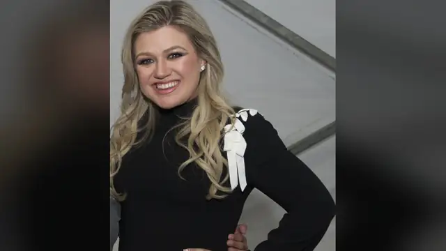 Kelly Clarkson smiling in a black dress with white bow trim at the 2018 Warrior Games