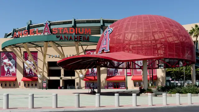 The front of Angel Stadium of Anaheim with its red halo letters and giant red baseball caps under a clear blue sky