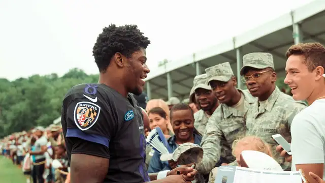 Ravens quarterback Lamar Jackson smiles while signing autographs for service members at a 2018 training camp practice