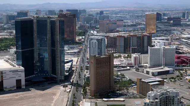 High-rise hotels and office towers spread across the Las Vegas Valley under a hazy sky with mountains on the horizon