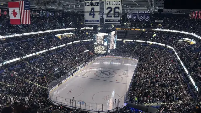 A packed crowd fills the Tampa Bay Lightning's home arena before a game with retired jerseys hanging above the ice