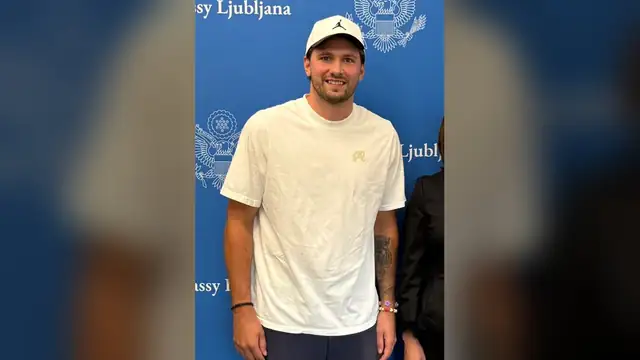 Luka Dončić smiles in a white T-shirt and white cap at the U.S. Embassy in Ljubljana in August 2026