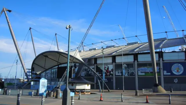 The blue exterior of the Etihad Stadium in Manchester under a clear sky