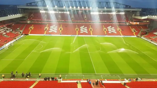 The pitch at Anfield in Liverpool under bright floodlights with the stands around it