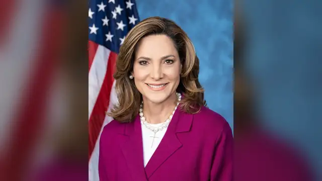 Rep. María Elvira Salazar smiles in her official portrait wearing a magenta jacket in front of an American flag