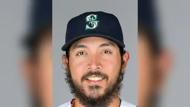 Andrés Muñoz smiling in a Seattle Mariners cap and white jersey