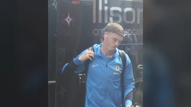 Cole Palmer in a blue Chelsea track jacket and shorts with a backpack on his shoulder arriving for a Premier League match