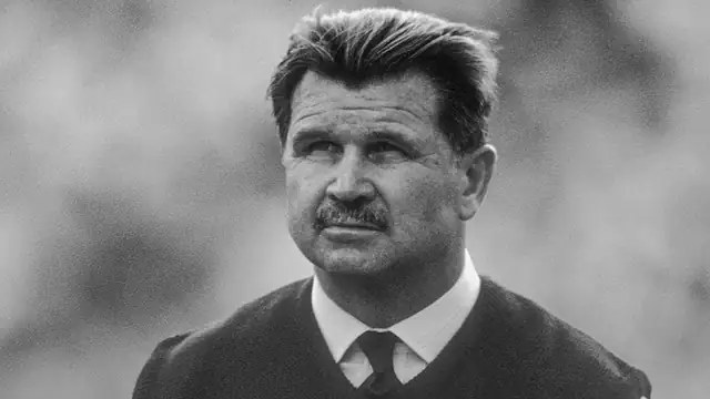 Black and white photo of Mike Ditka in a sweater and tie
