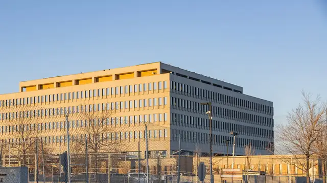 The Bishop Henry Whipple Federal Building near Minneapolis glowing in late-day sun behind a chain-link fence and bare winter trees