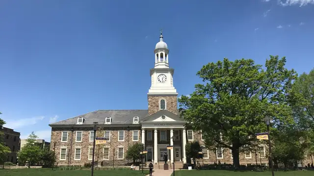 Holmes Hall with its clock tower and brick wings behind a green lawn on a sunny day at Morgan State University