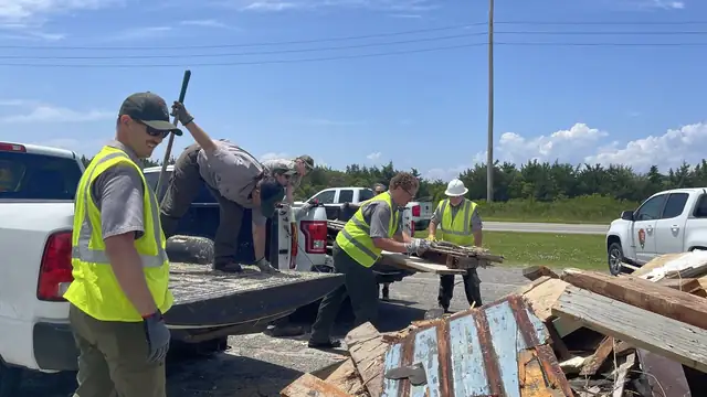 Workers in safety vests load broken lumber from a collapsed oceanfront house onto a truck in Rodanthe on the Outer Banks