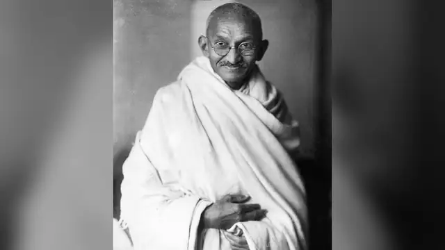 Mahatma Gandhi smiling in a white shawl in a 1931 black and white studio portrait