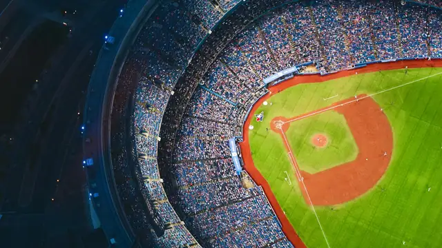 Aerial view of the Rogers Centre in Toronto at night with a packed crowd and the Blue Jays logo behind home plate