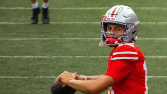 Ohio State quarterback Julian Sayin in a red Buckeyes jersey throws a pass on the field before a 2024 game
