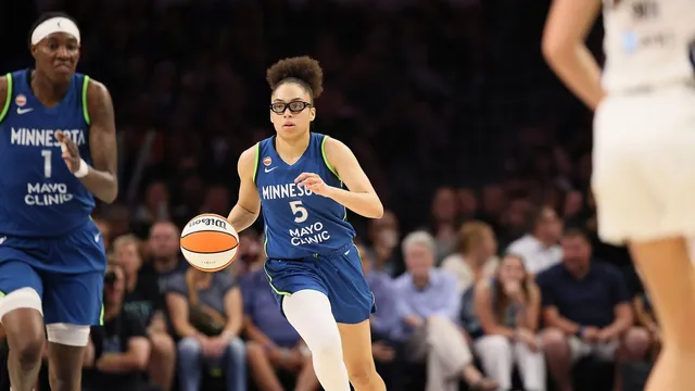 Minnesota Lynx guard Olivia Miles in a blue No. 5 jersey and goggles dribbles up the court at Target Center