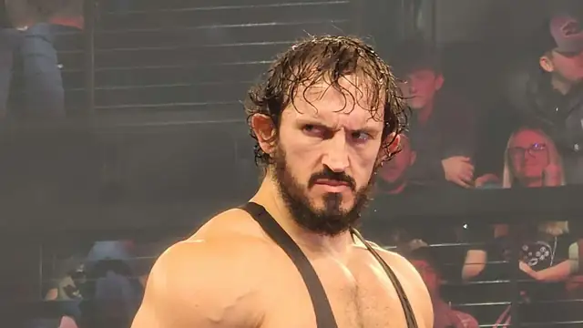 Wrestler PAC with wet hair and a beard in a wrestling arena