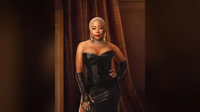 Pinky Cole posing in a black strapless leather gown with a jeweled headpiece