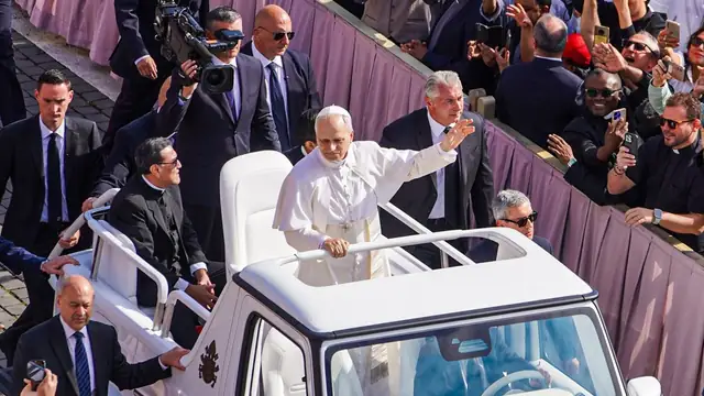 Pope Leo XIV waving to crowds from the popemobile in St. Peter's Square
