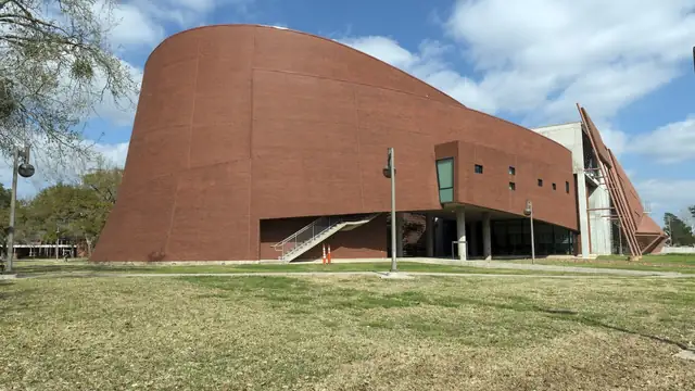 The curved terracotta-colored architecture and art building at Prairie View A&M University under a blue sky