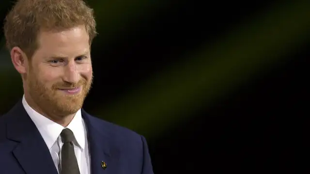 Prince Harry smiling in a dark suit